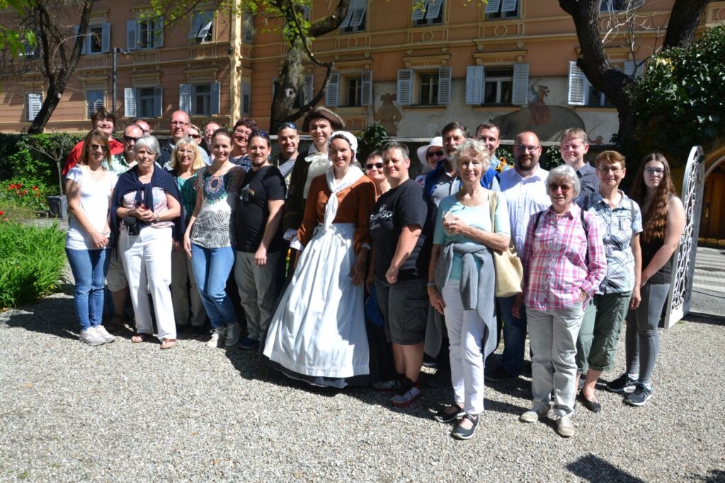 Eine Gruppe von Menschen in historischen Kostümen steht zusammen im Freien für ein Foto.