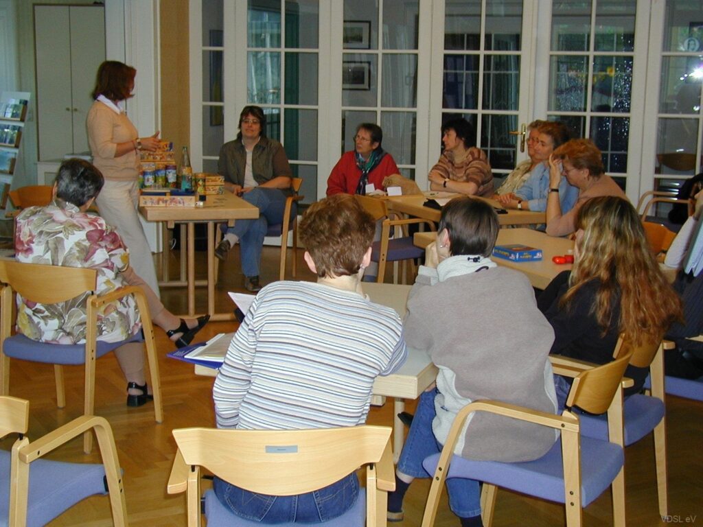 Eine Gruppe von Personen sitzt an einem Tisch und hört einer Präsentation zu.