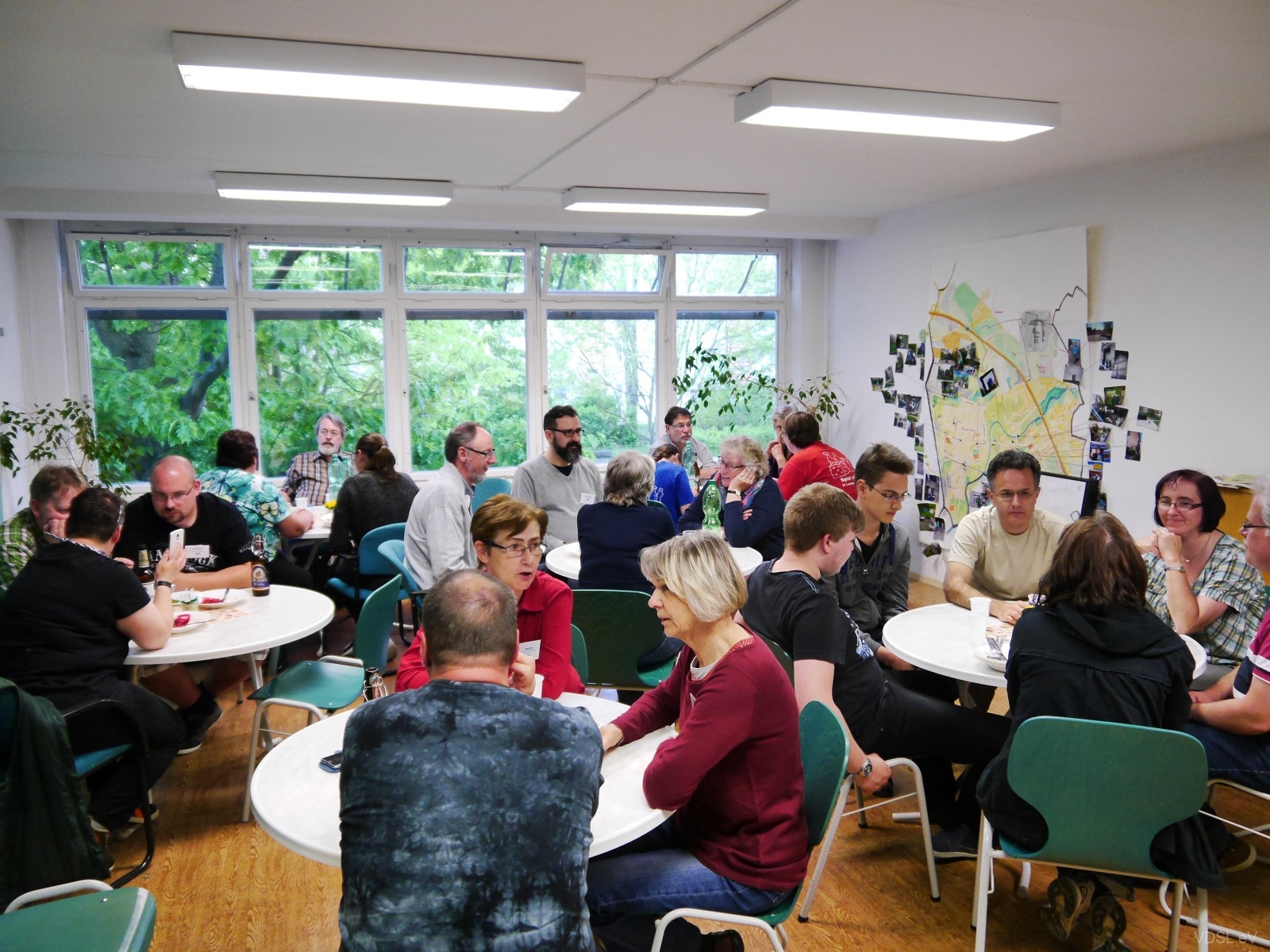 Menschen in einem Raum, die an Tischen sitzen und miteinander diskutieren.